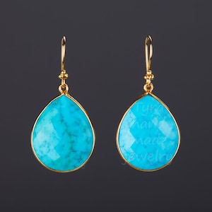 May include: A pair of gold dangle earrings with turquoise teardrop-shaped stones. The stones have a faceted cut and are set in gold.