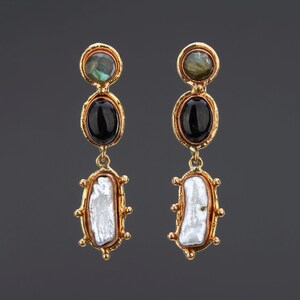 May include: Gold earrings with three stones each. The top stone is green, the middle stone is black, and the bottom stone is white.