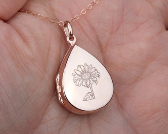 May include: Rose gold teardrop locket necklace with a delicate sunflower engraved on the front.