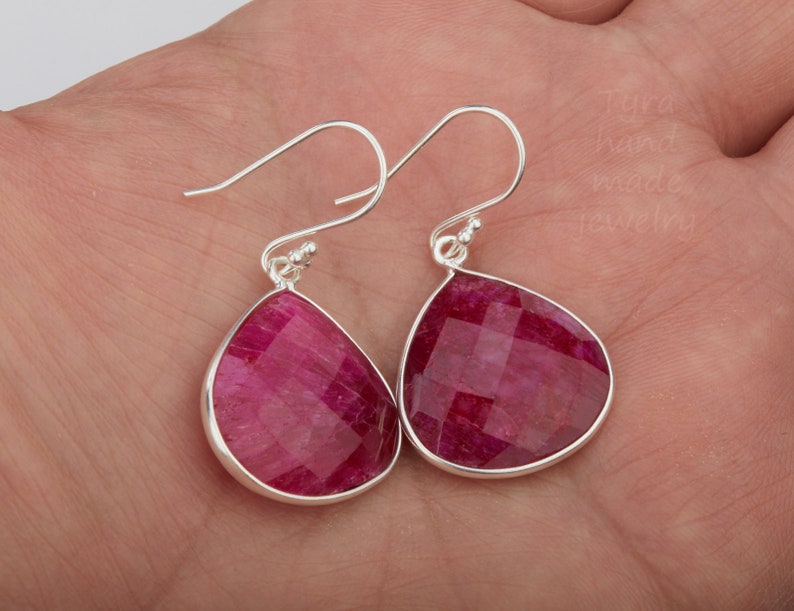 K&ouml;nnte beinhalten: Ein Paar silberne Tropfenohrringe mit facettierten rosafarbenen Rubin-Steinen.