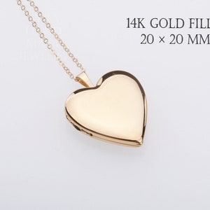 May include: A 14K gold filled heart-shaped locket pendant on a delicate gold chain. The text 14K GOLD FILLED 20 x 20 MM is printed in the upper right corner. The locket has a smooth, polished surface and a classic heart silhouette.