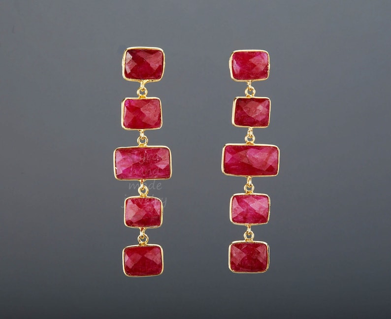 Puede incluir: Un par de pendientes largos y colgantes con m&uacute;ltiples gotas de piedras preciosas rojas. Cada pendiente tiene seis piedras preciosas rojas rectangulares conectadas por eslabones de oro.