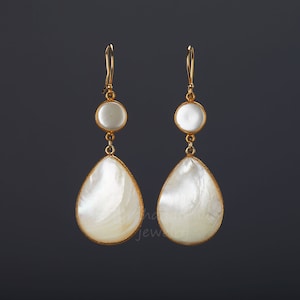 May include: A pair of gold tone earrings with white mother of pearl teardrop and round shaped drops.