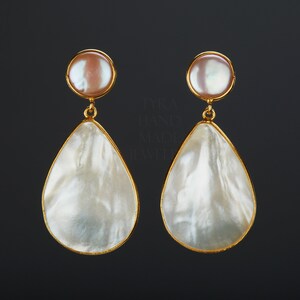May include: A pair of gold tone drop earrings with a white mother of pearl teardrop shape and a smaller round pearl at the top.
