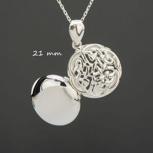 Puede incluir: Un collar con colgante de plata con un diseño de nudo celta. El colgante tiene 21 mm de diámetro y se abre para revelar un interior pulido. La cadena del collar también es plateada.