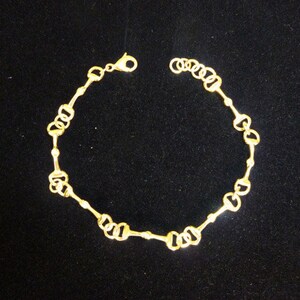 May include: A gold-toned bracelet with a chain made of interlocking horse bit-shaped links.