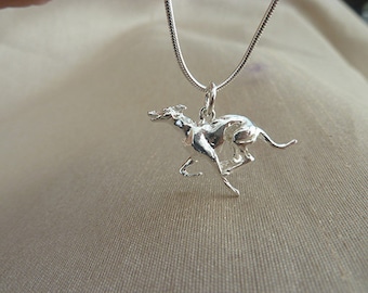 Puede incluir: Un collar de plata con un colgante de un galgo corriendo. El perro está en una pose realista con las patas extendidas y la cola enroscada.