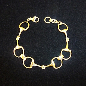 May include: Gold-toned bracelet made of linked horse bit charms.