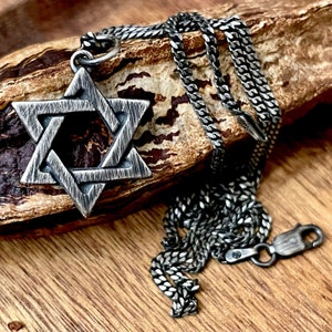 May include: A silver chain necklace with a silver Star of David pendant. The pendant has a textured, brushed finish.