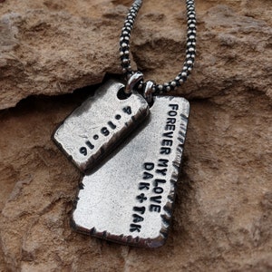 May include: Silver necklace with two dog tags. One tag says "Forever My Love Dak + Tak" and the other tag says "01.01.14".