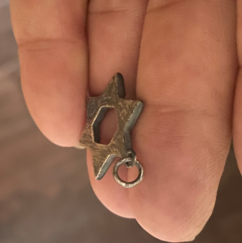 May include: A silver-toned Star of David pendant with a small ring attached to the bottom.