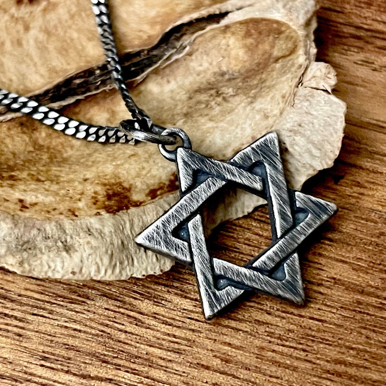May include: A silver Star of David pendant necklace with a textured finish. The pendant is on a silver chain.