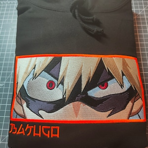 May include: Black hoodie with an orange embroidered image of an anime character with red eyes and the text "乃ムケムGロ" in orange.