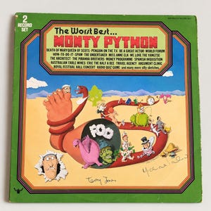 May include: A square vinyl record set cover titled The Worst Best... Monty Python. The green cover features a large cartoon foot, a pink creature, and various small figures on a desert landscape. It includes a list of sketches and signatures.