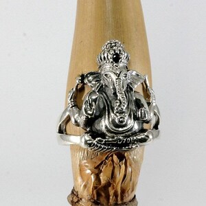 Könnte beinhalten: Silberring mit einer detaillierten Darstellung der hinduistischen Gottheit Ganesha, mit einem roten Edelstein in seiner Krone.
