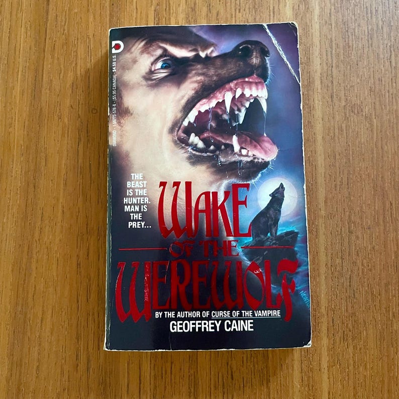 May include: A vintage paperback book titled "Wake of the Werewolf" by Geoffrey Caine. The cover features a snarling wolf head, a howling wolf silhouette, and the text "The Beast is the Hunter. Man is the Prey..."