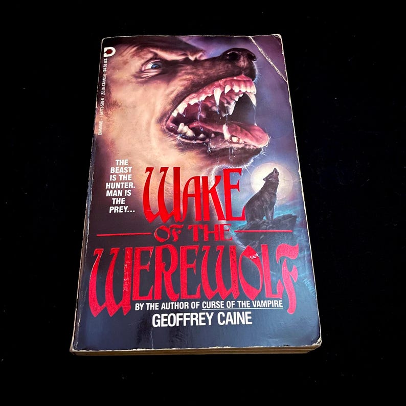 May include: A paperback book titled "Wake of the Werewolf" by Geoffrey Caine. The cover features a snarling werewolf head with bared teeth and a howling wolf silhouette under a full moon. The text "The beast is the hunter. Man is the prey..." is also visible.