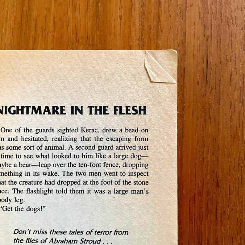May include: A close-up of a book page with the title "NIGHTMARE IN THE FLESH" in bold black letters. The text describes a suspenseful scene with guards and a mysterious creature. The page has a torn corner.