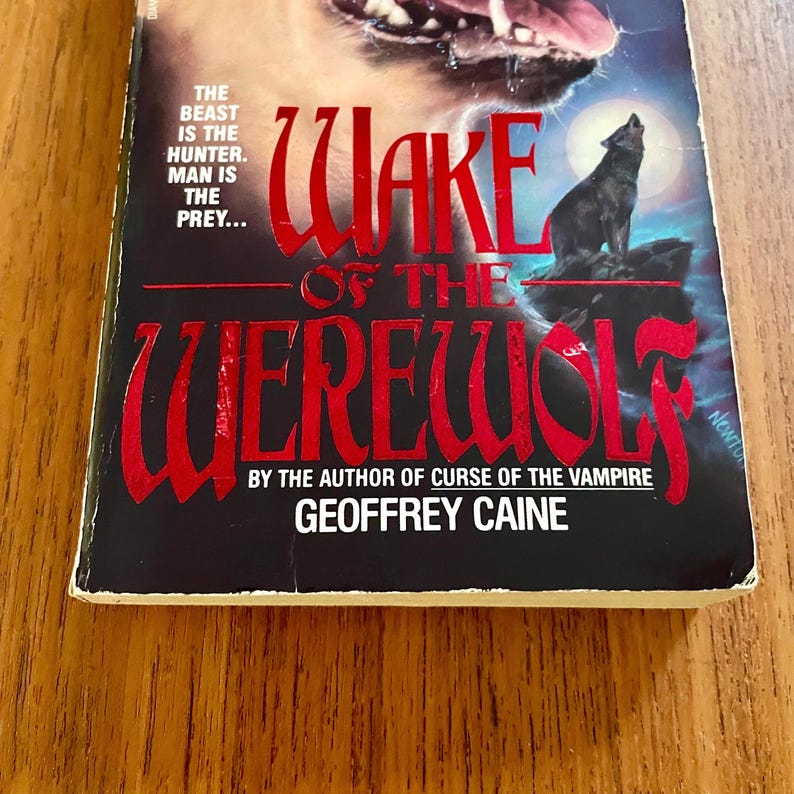 May include: A paperback book titled "Wake of the Werewolf" by Geoffrey Caine. The cover features a red title against a black background, with a howling wolf silhouette under a full moon. The text "The Beast is the Hunter. Man is the Prey..." is also visible.
