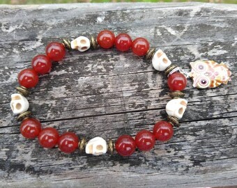 May include: A red carnelian stone bracelet with white skull beads and a gold owl charm.