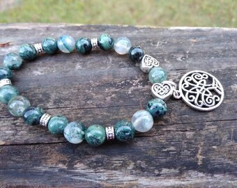 May include: A green and white agate stone bracelet with a silver Celtic knot charm. The bracelet is made with round beads and has a silver spacer bead between each stone.