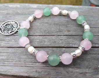May include: A bracelet with pink and green beads, silver spacers, and a silver charm with a floral design.