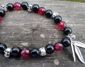 May include: Black and red beaded bracelet with silver skull and feather charms.