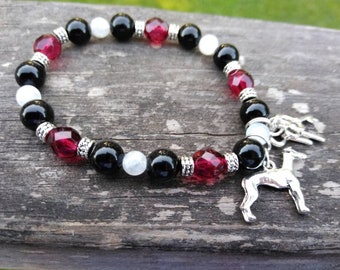 May include: Black, white, and red beaded bracelet with a silver greyhound charm. The bracelet has silver accents between each bead.