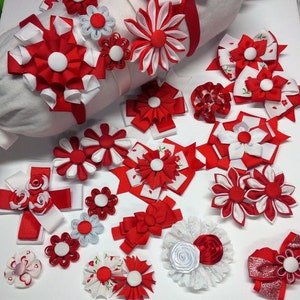 May include: A collection of red and white fabric flowers, some with a center of white and others with a center of red. The flowers are arranged on a white surface.