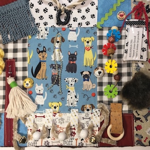 May include: A blue and white fabric baby activity mat with a variety of textures and features for babies to explore. The mat features a variety of dog illustrations, a zipper, a pocket, a tag with the text "BELONGS TO: Insert your loved one's name in pocket", a variety of textures, and a variety of colors.