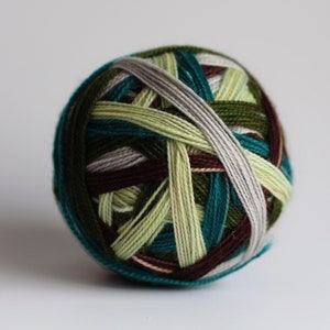 May include: A ball of yarn with a complex, interwoven pattern of various colors. The yarn features shades of green, teal, brown, and gray, creating a visually appealing and textured appearance. This yarn is suitable for knitting and crochet projects.