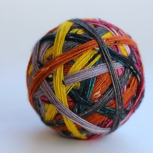 Può includere: Un gomitolo di lana colorato con una varietà di colori tra cui giallo, arancione, grigio e rosa. La lana è avvolta strettamente, creando una forma sferica. Adatto per progetti di maglia e uncinetto.