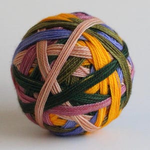 May include: A colorful ball of yarn with interwoven strands of various colors, including yellow, green, purple, pink, and brown. The yarn is tightly wound, creating a textured, spherical shape. Ideal for knitting and crochet projects.