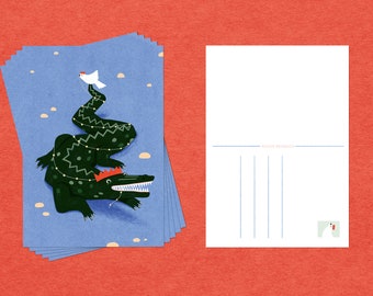 May include: A stack of blue postcards featuring a green alligator wearing a red crown and a white bird perched on its tail. The alligator is decorated with a string of lights.