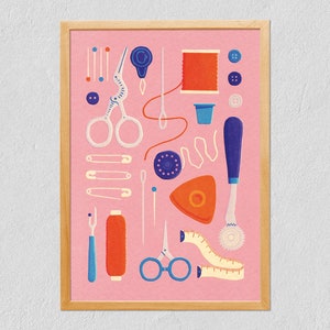 Op de afbeelding: Een ingelijste print met diverse naai-attributen op een roze achtergrond. De afbeelding toont scharen, naalden, garen, knopen, een meetlint en een tornmesje. Het kunstwerk is in een vintage, illustratieve stijl.