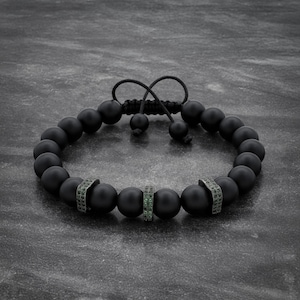 Puede incluir: Pulsera de cuentas negras mate con tres espaciadores plateados adornados con pequeñas piedras preciosas verdes. La pulsera tiene un cierre de cordón negro ajustable. Las cuentas tienen aproximadamente 1 cm de diámetro.