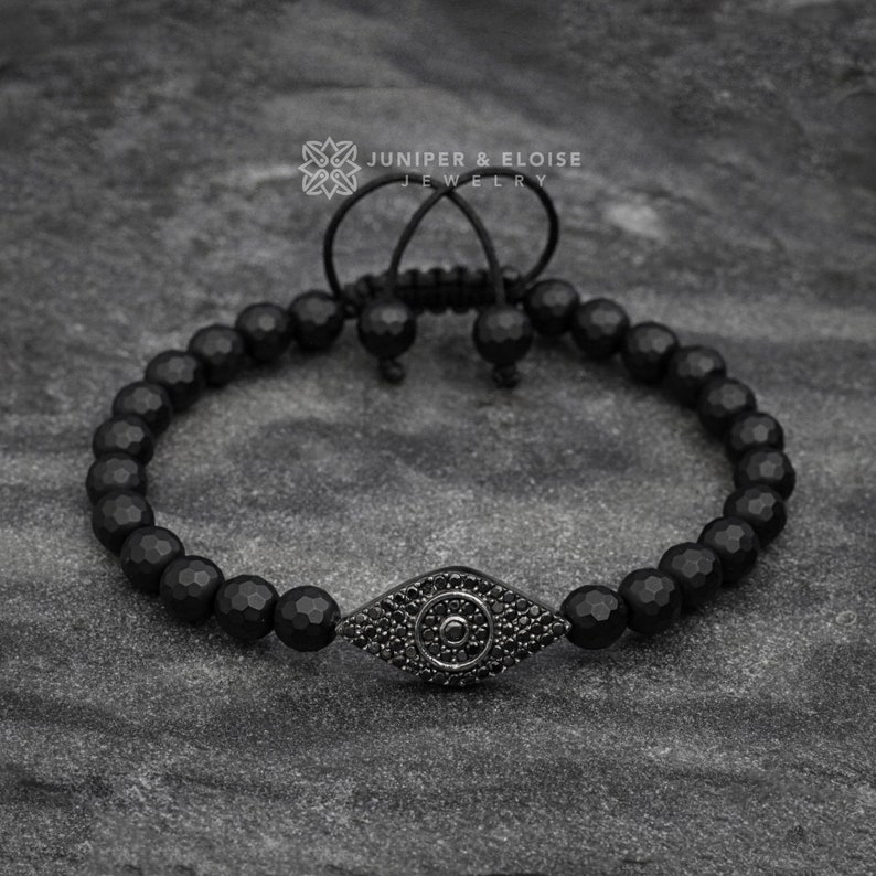 Sleek black 925 silver evil eye bracelet with faceted 6mm onyx beads, enhanced with black zircon stones. Adjustable macrame knot for a secure fit. Perfect for protection and style