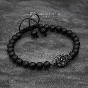 Simple yet elegant evil eye bracelet made with 6mm faceted onyx beads and a 925 silver evil eye charm, accented with black zircon stones. Adjustable macrame knot for easy wear