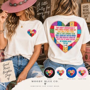 Peut inclure: Un t-shirt couleur crème avec un petit cœur en patchwork sur la poitrine gauche et un grand cœur en patchwork au dos contenant le texte : They didn't understand it and I tried to make them see that one is only poor only if they choose to be now I know we had no money but I was rich as I could be in my coat of many colors my momma made for me.