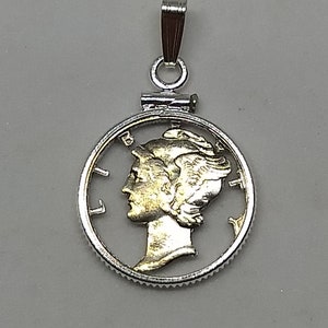 May include: Silver pendant featuring a cutout of a silver coin with a gold-toned image of a woman's profile. The coin has the inscription "LIBERTY" on the left side.
