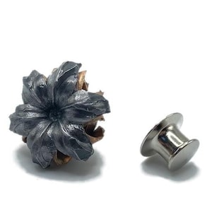May include: A black and silver bullet-shaped pin with a star-shaped design. The pin is made of metal and has a silver finish. The bullet is a hollow point and has a star-shaped design on the front. The pin is a great way to show your love for guns and hunting.