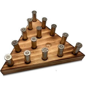 May include: A wooden triangle-shaped game board with brass bullet casings as pegs. The board is made of light brown wood and has a single hole in the center. The bullet casings are arranged in a triangular pattern.