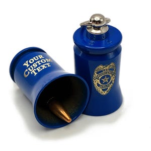 May include: Two blue metal containers with a silver top and a gold emblem that says "Law Enforcement Officer". One container has the text "YOUR CUSTOM TEXT" in gold. A bullet is inside one of the containers.