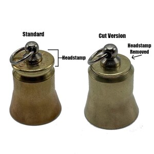 May include: Two brass-colored bell-shaped objects. The left one is labeled "Standard" and has a "Headstamp." The right one is labeled "Cut Version" with the "Headstamp Removed." Each has a small metal ring attached to the top.