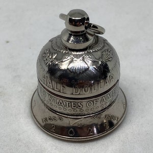 May include: A silver bell with a United States Half Dollar coin design. The bell is engraved with "Half Dollar", "United States of America", "In God We Trust", and "2022".