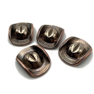 May include: Four silver-colored Texas state quarter coins have been transformed into cowboy hats. Each coin has been embossed with a cowboy hat design and the words "Texas 1845" and "2004 E Pluribus Unum".
