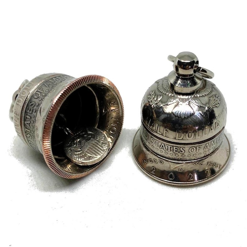 May include: Two silver bells made from half dollar coins. The bell on the left is open, showing the coin inside. The bell on the right is closed and has the inscription "Half Dollar" and "United States of America" around the rim.