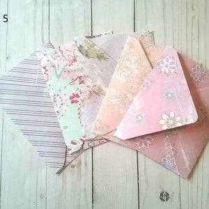 May include: Pack of five decorative envelopes with different floral patterns. The envelopes are pink, green, and white with a variety of floral designs.