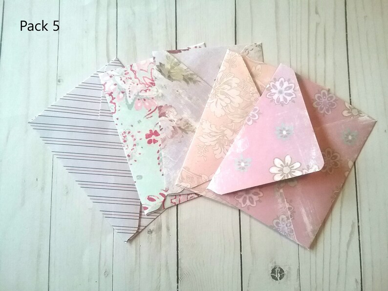 May include: Pack of five decorative envelopes with different floral patterns. The envelopes are pink, green, and white with a variety of floral designs.