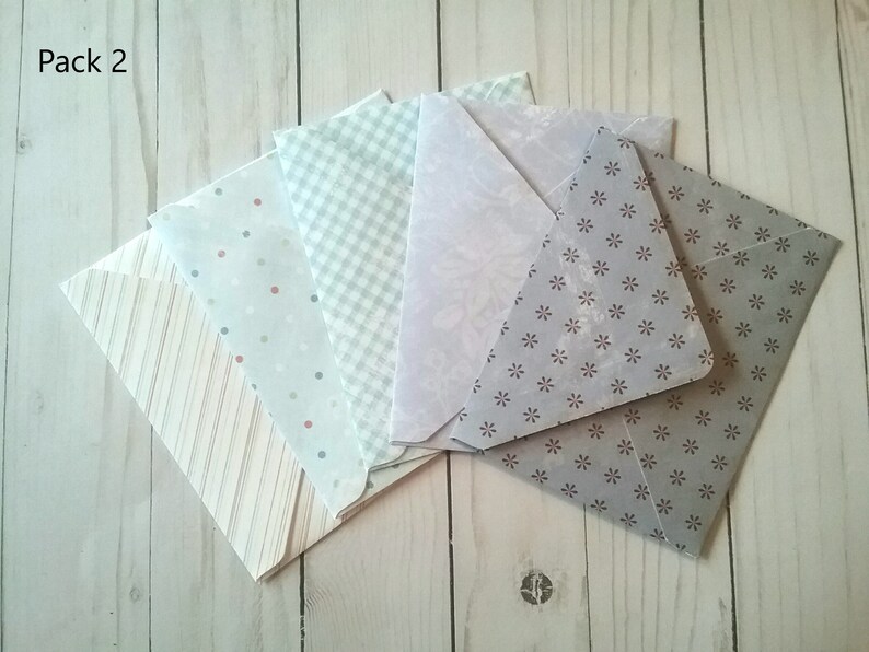 May include: Pack of six envelopes with different patterns. The envelopes are in shades of gray, white, and blue. The patterns include stripes, polka dots, gingham, and a floral design.